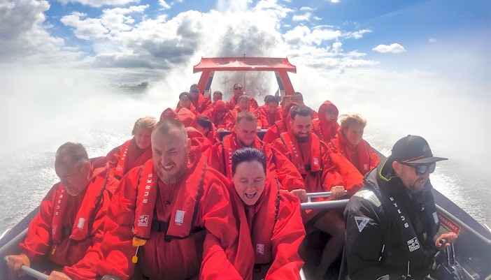 Group enjoying OZ Jet Boating ride in Sydney, water splashing around.