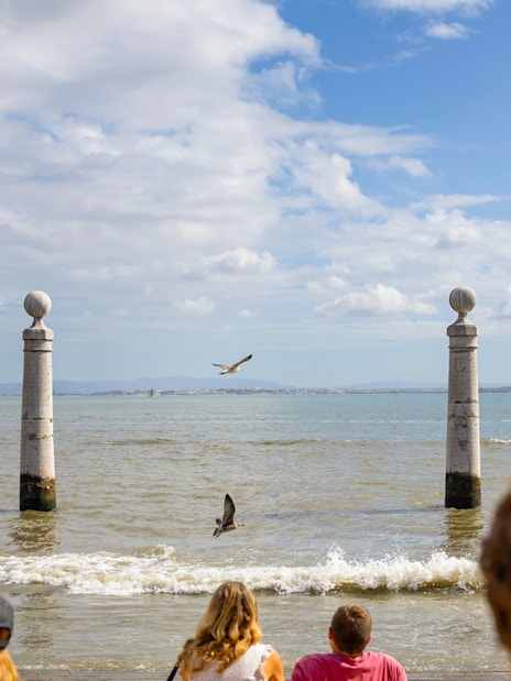 Young people relaxing on marble steps at Cais das Colunas, Praca do Comercio, Lisbon.