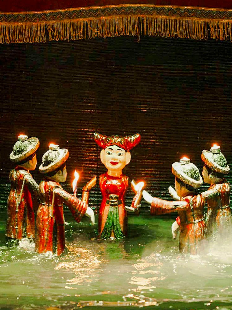 Water puppets holding candles on a misty stage at Thang Long Water Puppet Theatre, Hanoi.