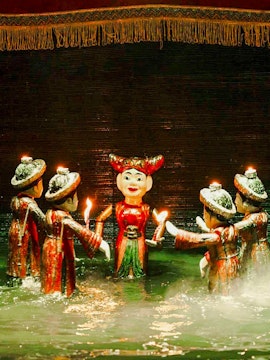 Water puppets holding candles on a misty stage at Thang Long Water Puppet Theatre, Hanoi.