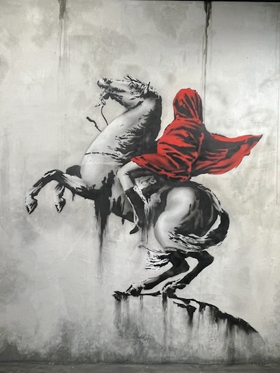 Banksy artwork of a hooded figure on a rearing horse at Amsterdam museum.