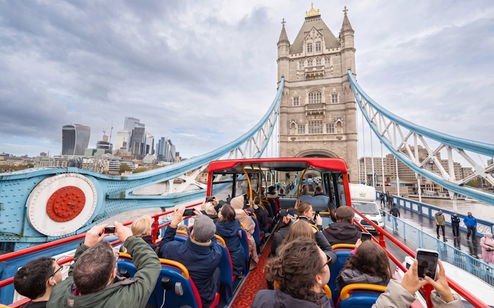 Open-top bus tour crossing Tower Bridge in London.