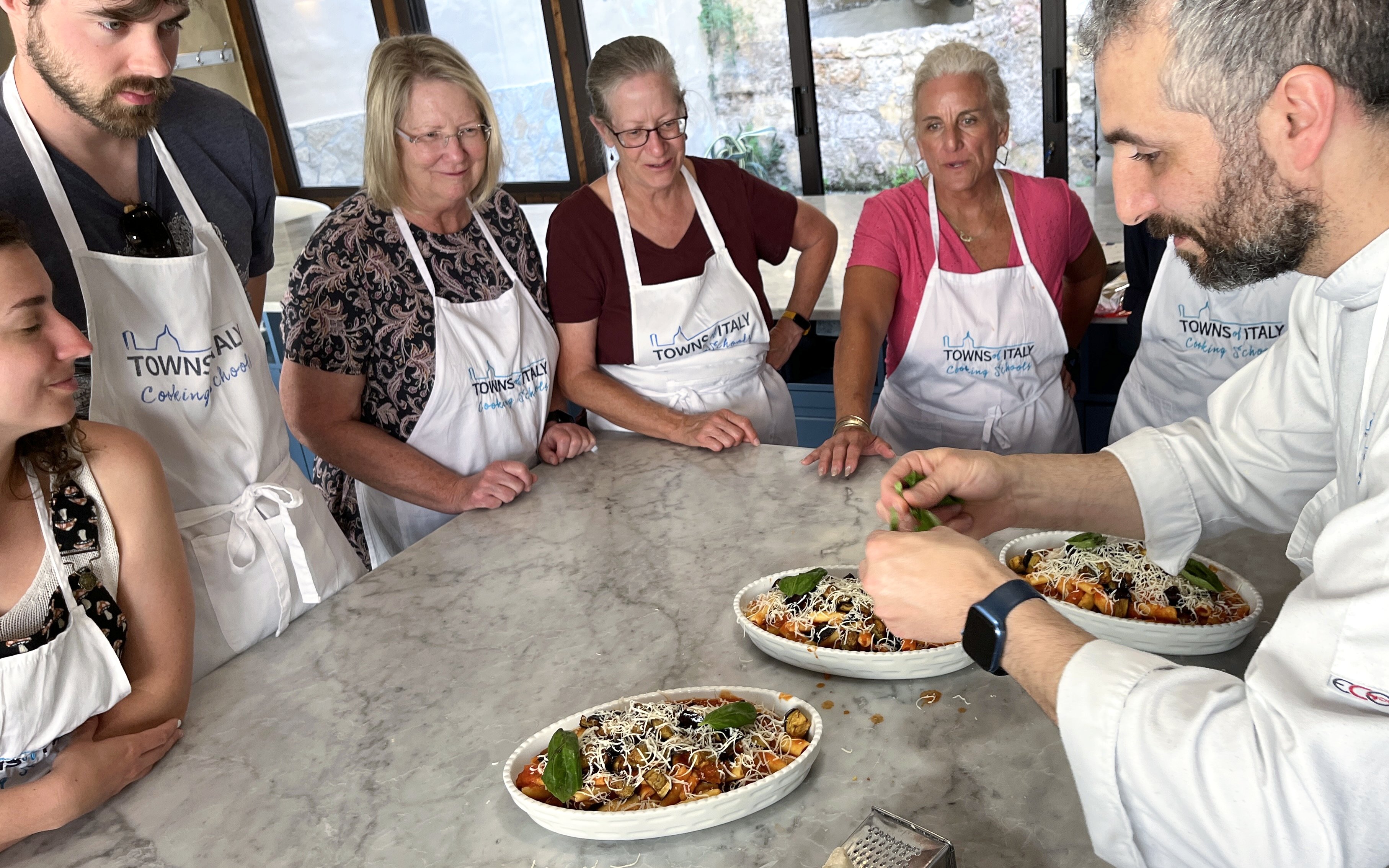 Participants in a Palermo cooking class watch a chef prepare pasta dishes.
