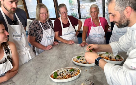 Participants in a Palermo cooking class watch a chef prepare pasta dishes.