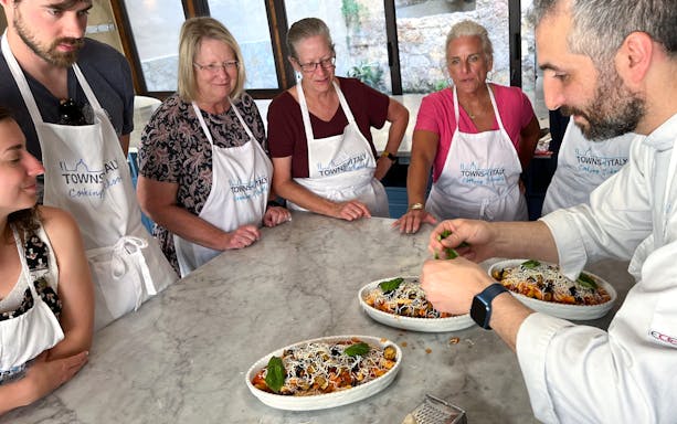 Participants in a Palermo cooking class watch a chef prepare pasta dishes.