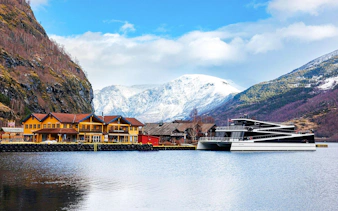 Flam village waterfront with yellow buildings and a boat, Norway fjord backdrop.