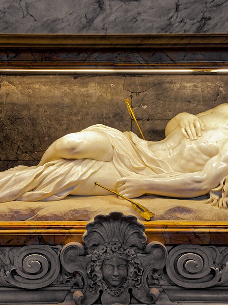 Marble sculpture of a reclining figure with arrows, St. Peter’s Basilica tour.