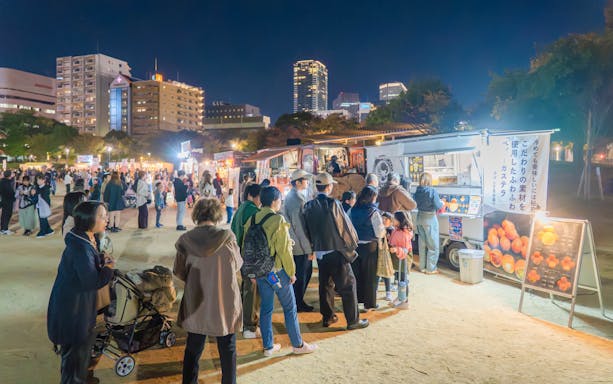 Crowd at food stalls during Ōgimachi Sakura Festival at night in urban setting.