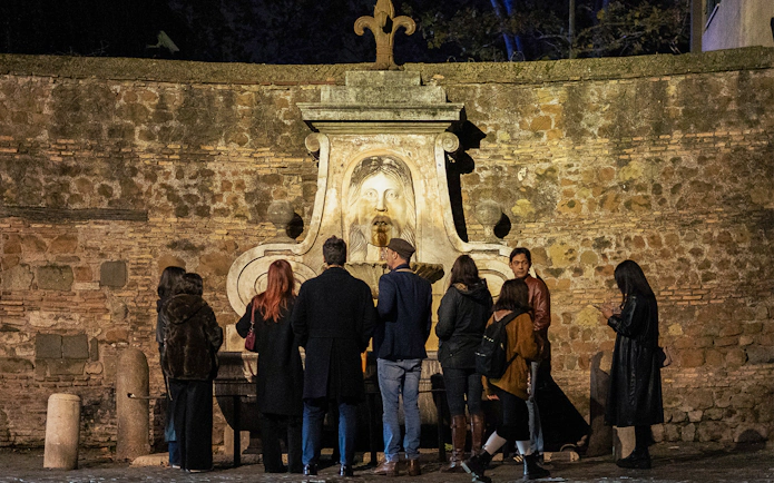 Group of tourists at the Mouth of Truth during a haunted ghosts tour in Rome.