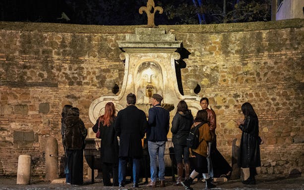 Group of tourists at the Mouth of Truth during a haunted ghosts tour in Rome.