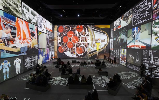 Moonwalkers Exhibition at Atelier des Lumières featuring Apollo mission visuals and audience.