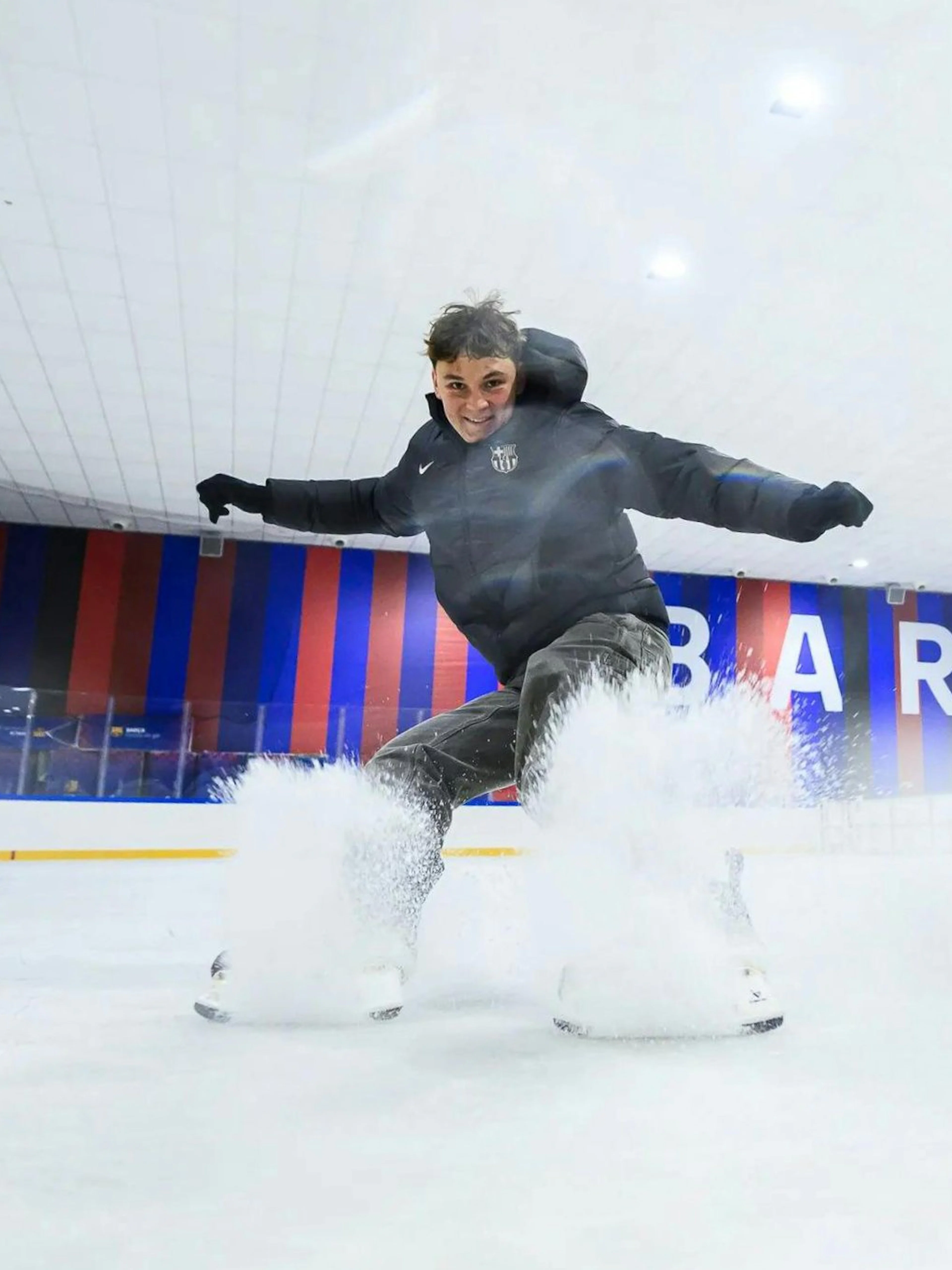 Ice skater performing at FC Barcelona Ice Rink with Barcelona signage in the background.