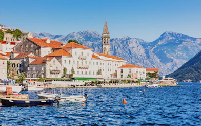 Historic waterfront buildings and boats in Perast, Montenegro, with mountains in the background.