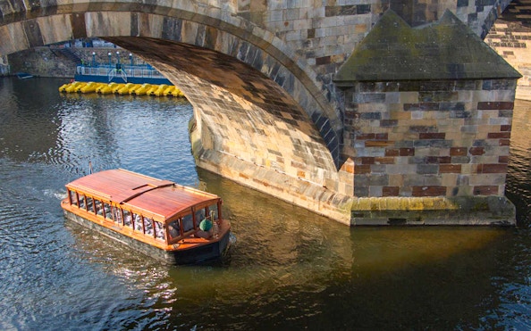 Boat cruising under Charles Bridge in Prague.