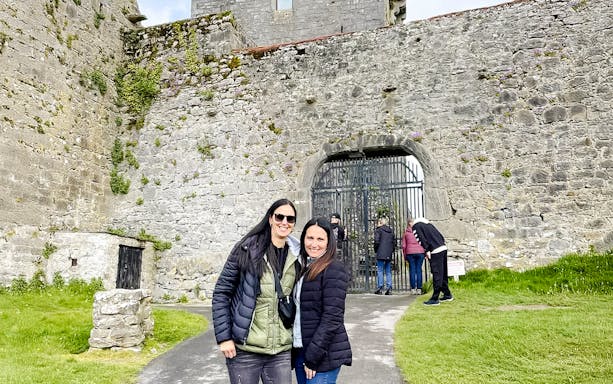 Visitors exploring the entrance of Dunguaire Castle in Ireland.