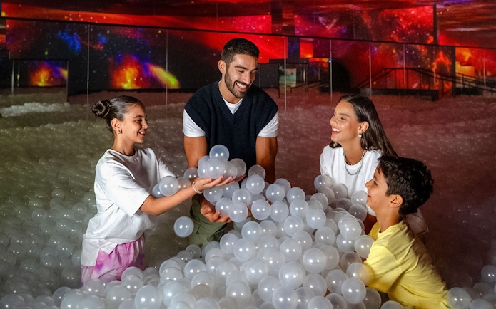 Family enjoying interactive ball pit at AYA Universe.