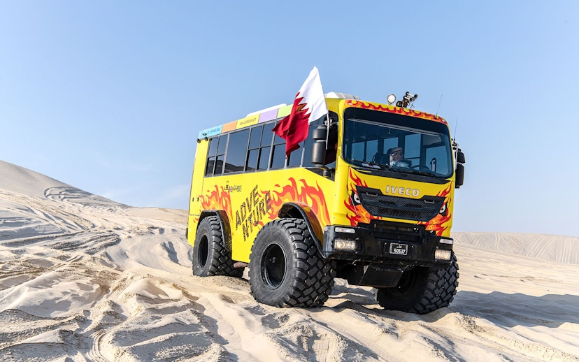 Monster bus driving through sand dunes in Doha, Qatar.