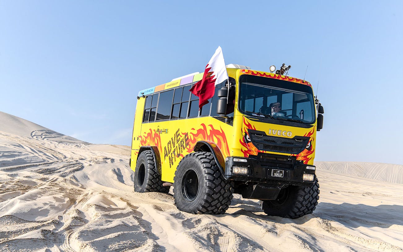 Monster bus driving through sand dunes in Doha, Qatar.