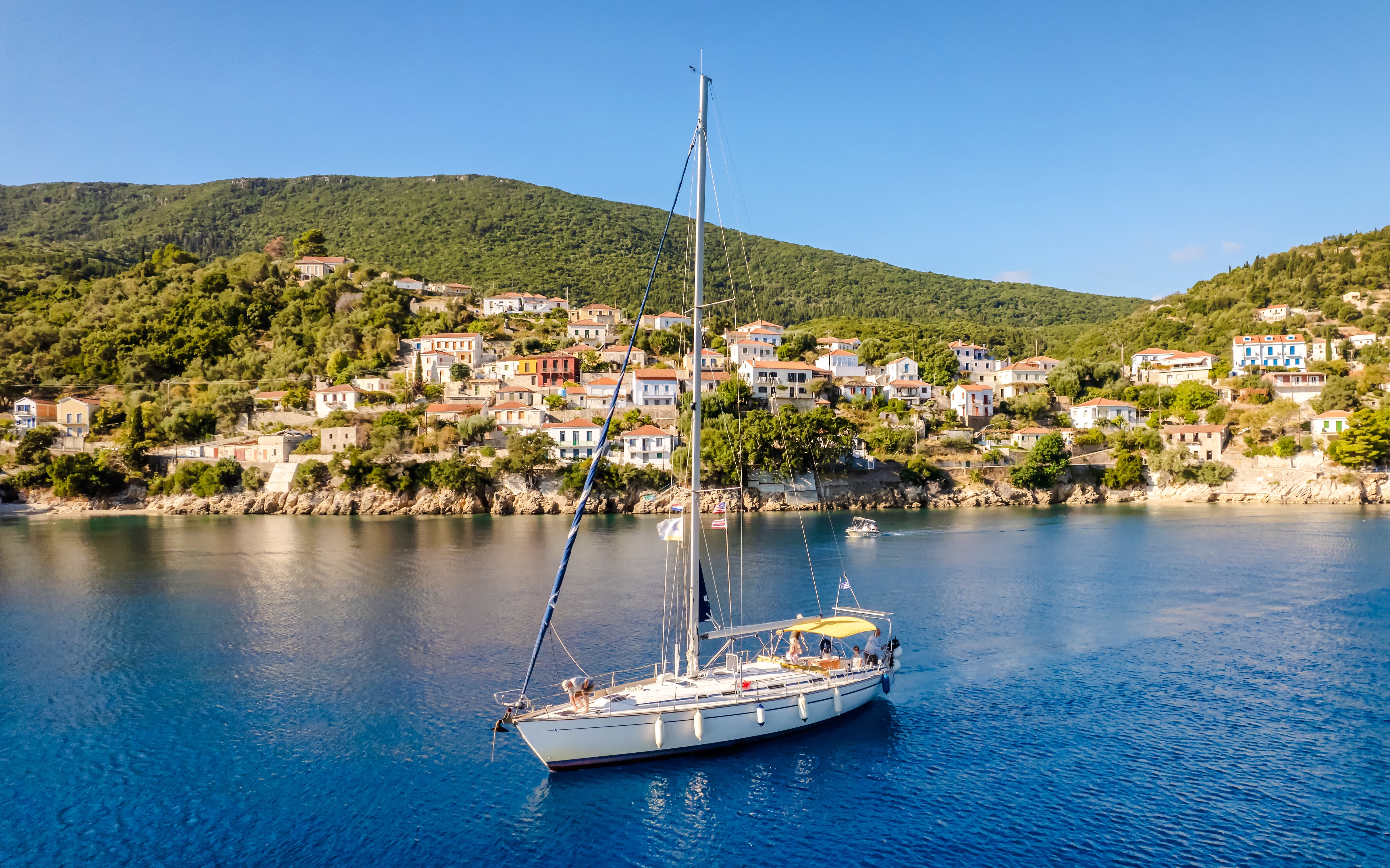 Sailing boat in the bay of Kioni, Greece with hillside village in the background.