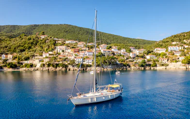 Sailing boat in the bay of Kioni, Greece with hillside village in the background.