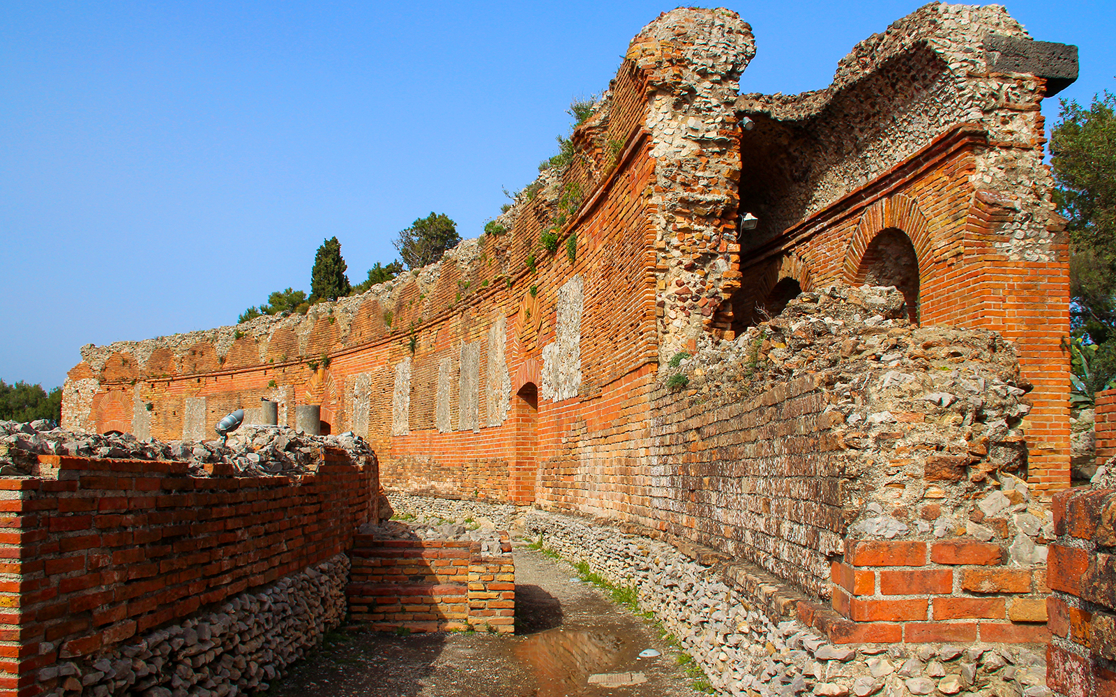 Taormina Ancient Theatre ruins with stone arches and brick walls, Sicily.