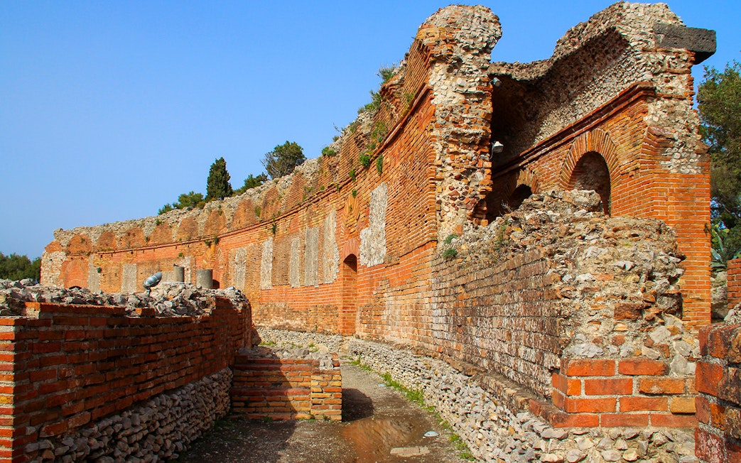 Taormina Ancient Theatre ruins with stone arches and brick walls, Sicily.
