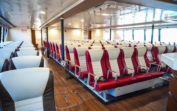 Interior seating of Majestic Fast Ferry with rows of red and white seats.