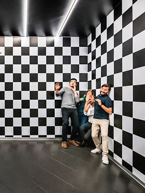 Visitors experiencing optical illusion in the Ames Room at Illuseum Berlin.