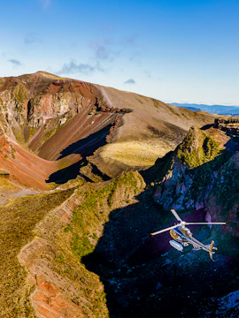 Helicopter flying over Mount Tarawera's volcanic crater in New Zealand.
