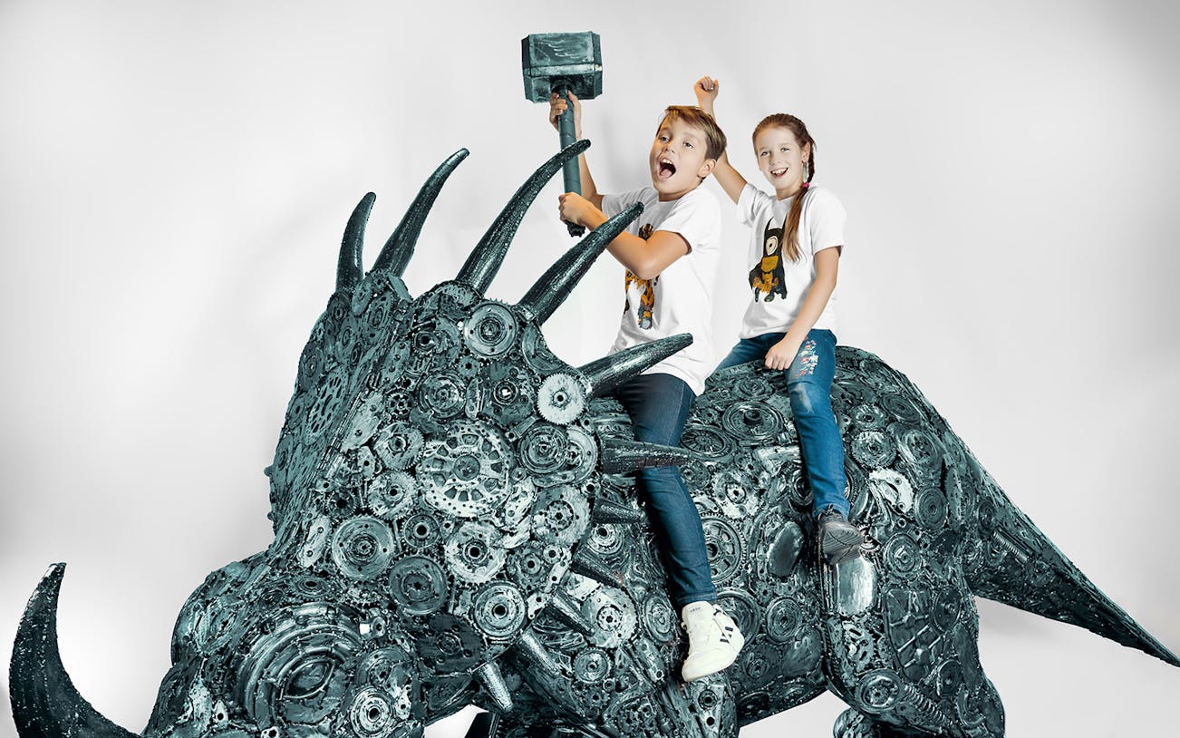 Children on a metal sculpture of a dinosaur at the Gallery of Steel Figures, Prague.