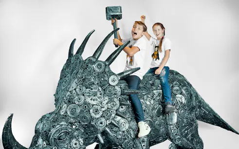 Children on a metal sculpture of a dinosaur at the Gallery of Steel Figures, Prague.