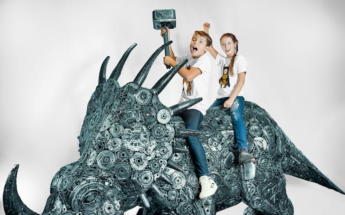 Children on a metal sculpture of a dinosaur at the Gallery of Steel Figures, Prague.
