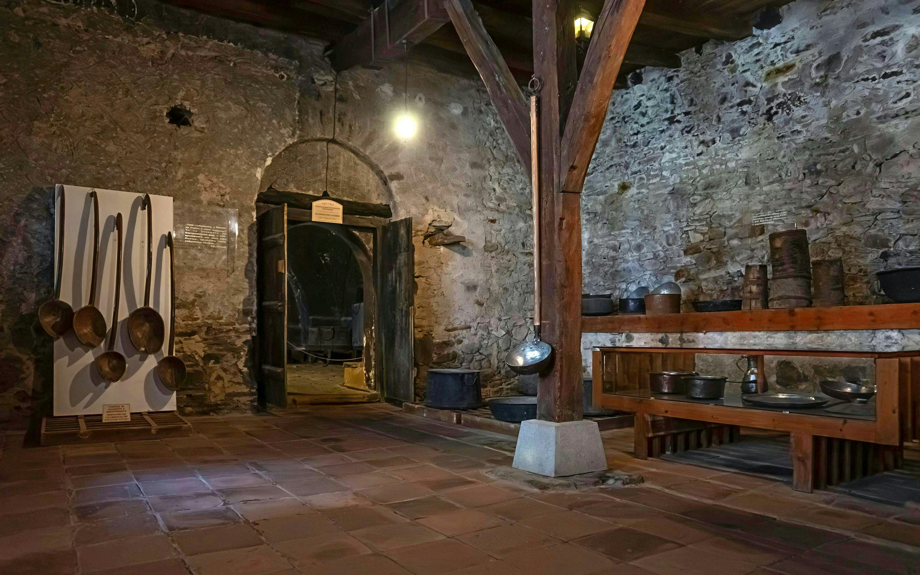Monastery kitchen interior with large ladles and rustic stone walls, Rila Monastery, Bulgaria.