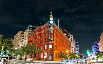 Historic red brick building illuminated at night in Washington DC, part of self-guided city exploration game.