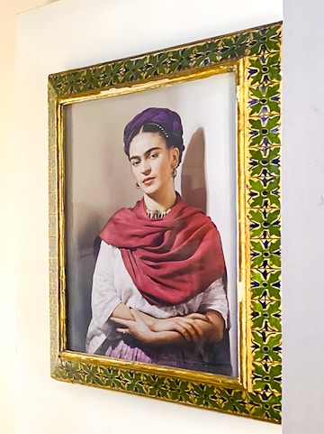 Frida Kahlo portrait in ornate frame at Frida Kahlo Museum, Mexico City.