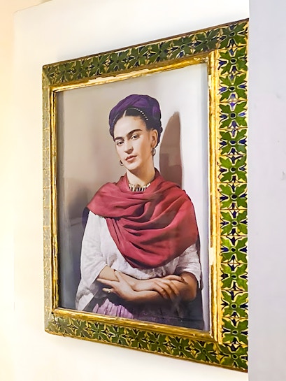 Frida Kahlo portrait in ornate frame at Frida Kahlo Museum, Mexico City.