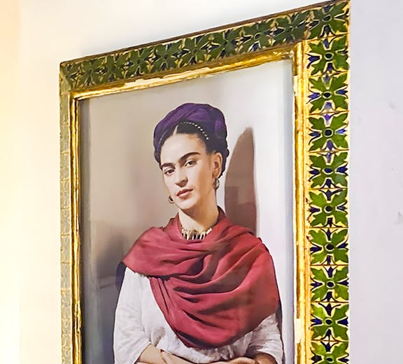 Frida Kahlo portrait in ornate frame at Frida Kahlo Museum, Mexico City.