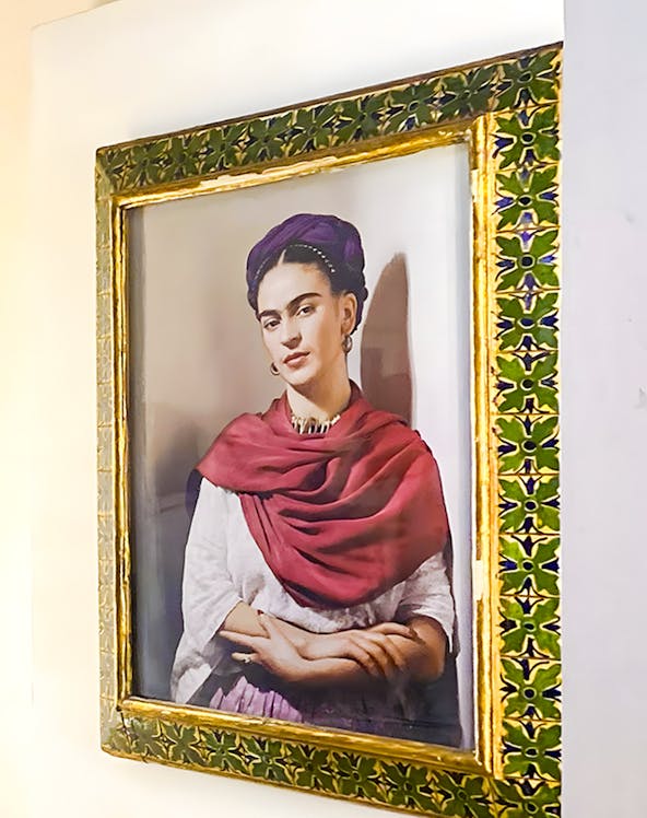 Frida Kahlo portrait in ornate frame at Frida Kahlo Museum, Mexico City.