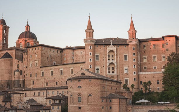 Urbino's Ducal Palace with its distinctive towers at sunset.