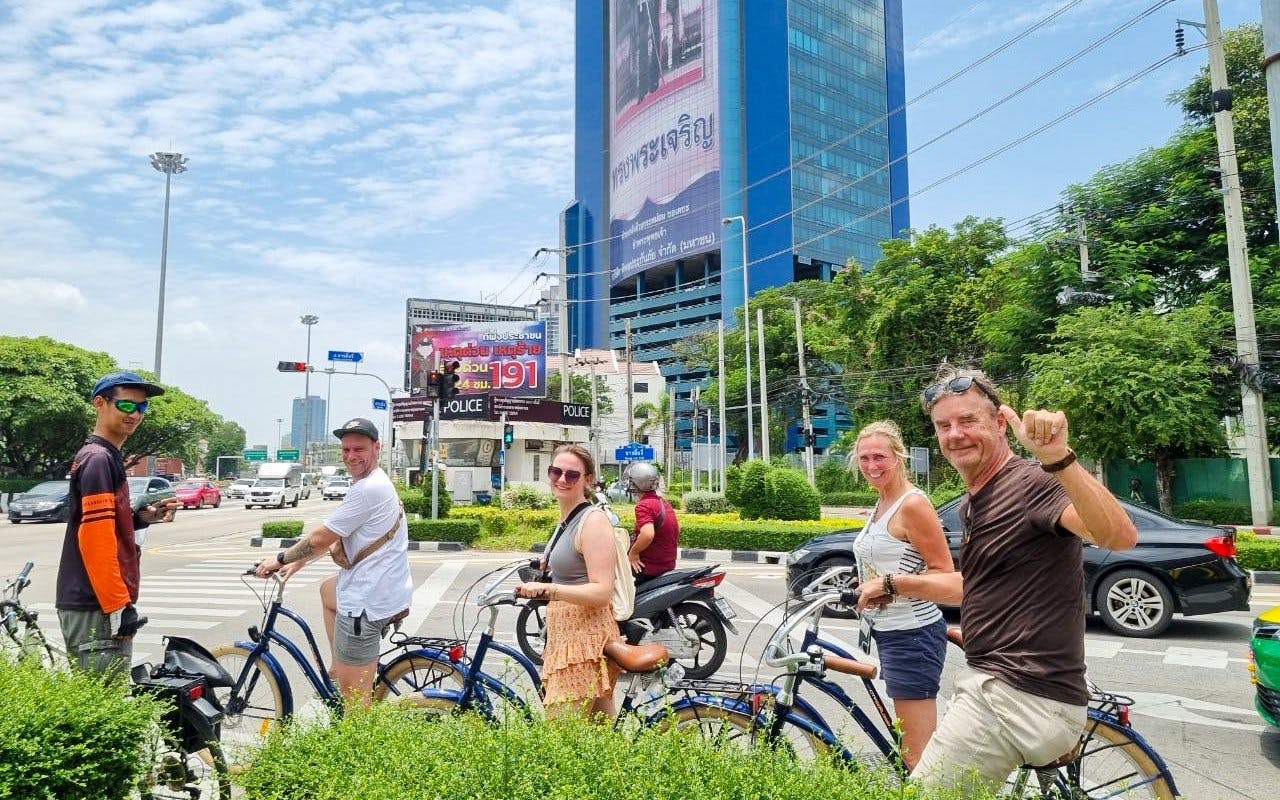 Tourists on bicycles exploring Bangkok city streets with a large building in the background.