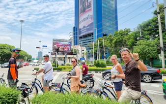 Tourists on bicycles exploring Bangkok city streets with a large building in the background.