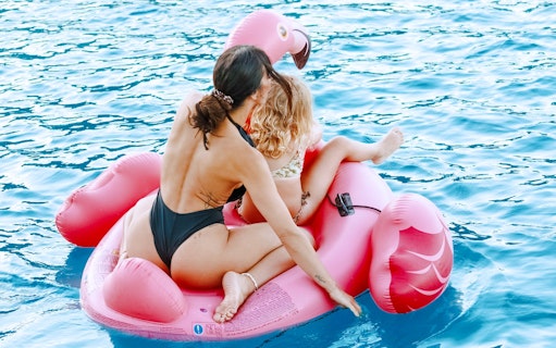 Two people on a pink inflatable flamingo in the water during a Catamaran Cruise near Spinalonga, Crete.