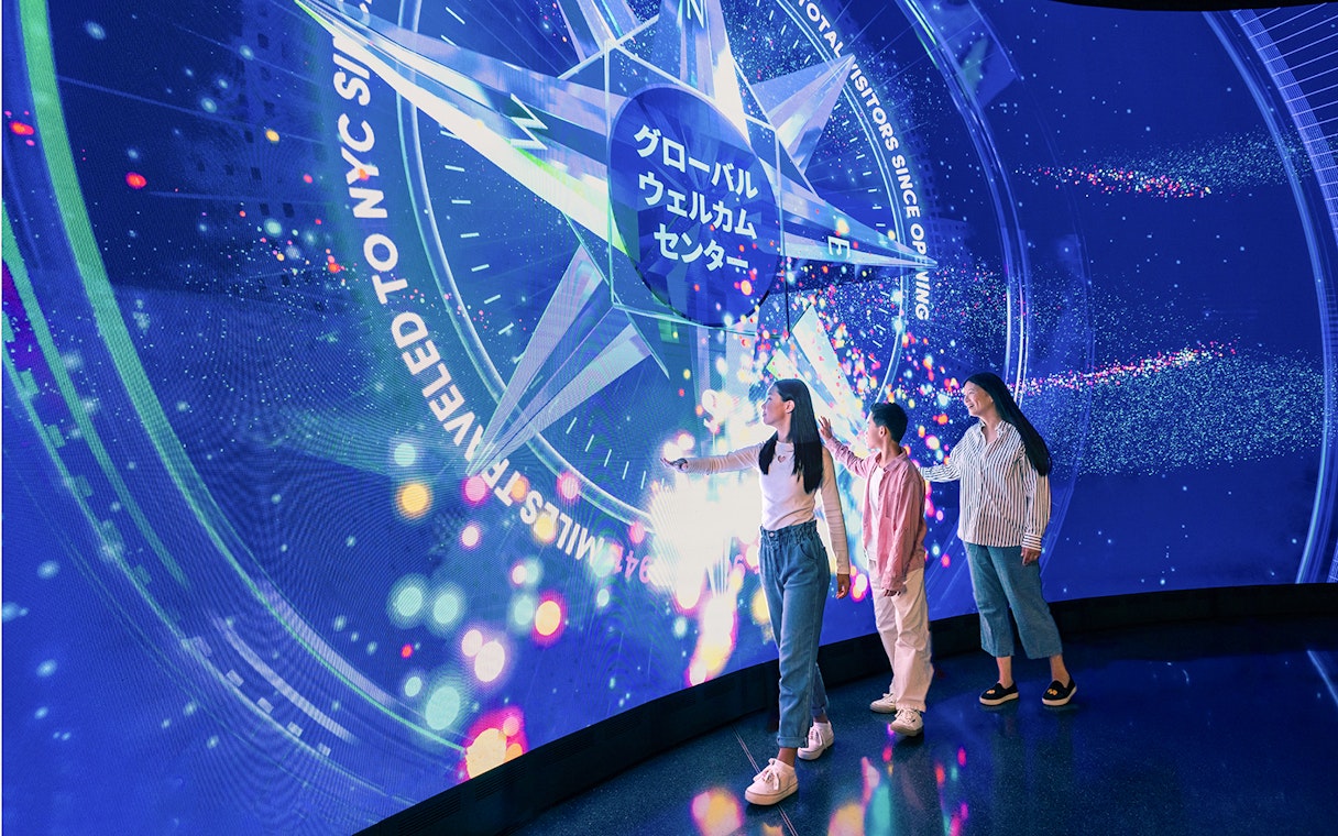 Visitors interacting with digital display at One World Observatory, New York City.