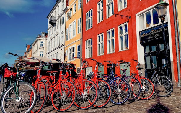 Bicycles lined up in front of colorful buildings on a Copenhagen street.