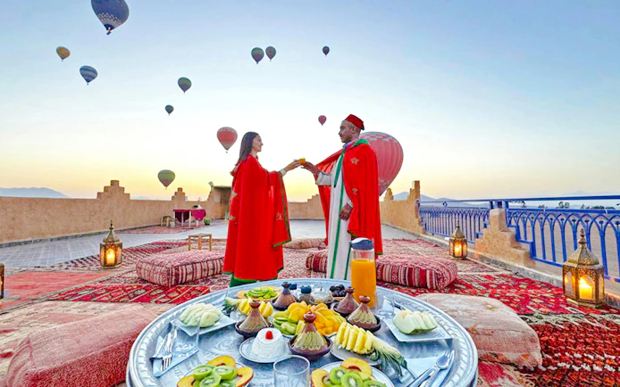 Lunch setup on a rooftop with hot air balloons in Marrakech.