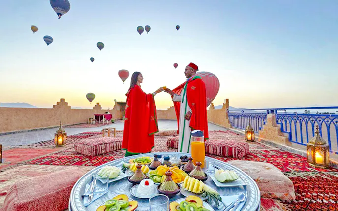 Lunch setup on a rooftop with hot air balloons in Marrakech.