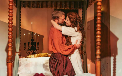 Couple embracing in historical attire beside a candlelit bed, Willem van Oranje theme.