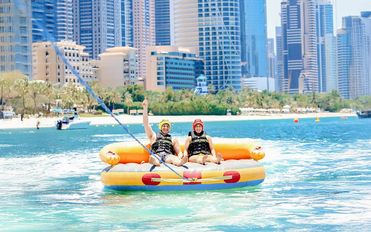 Men on a donut ride in Dubai with city skyline in the background.