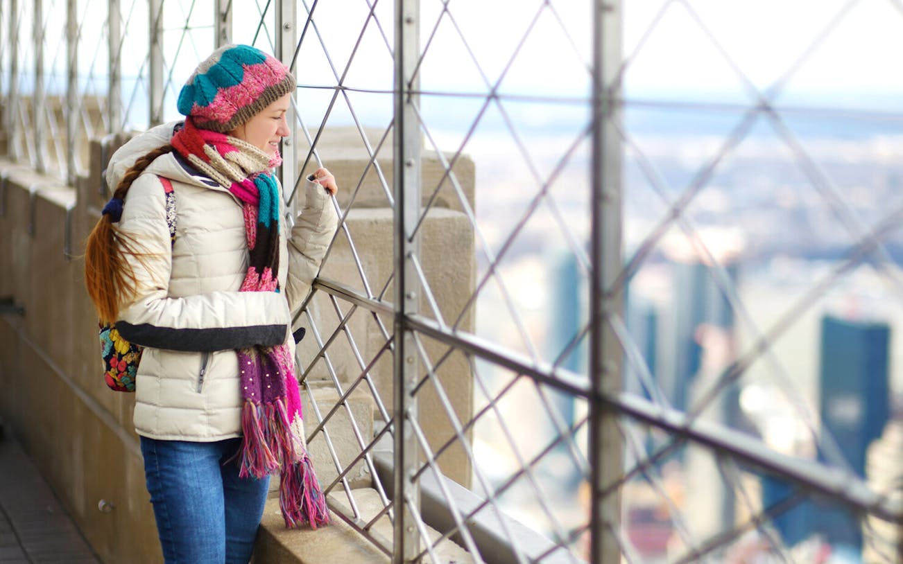 Person enjoying view from Empire State Building observation deck, New York City.