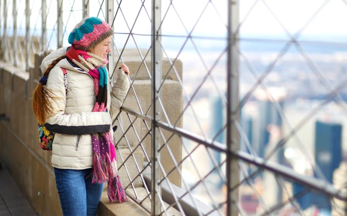 Person enjoying view from Empire State Building observation deck, New York City.